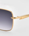 Close-up of the Edge sunglasses by For Art's Sake® featuring gold metal frames, gradient dark lenses, and detailed hinge and temple arms. The minimalist square silhouette is displayed against a light gray background.