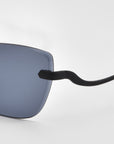 Close-up of the left side of For Art's Sake® Spark sunglasses, showing a dark rectangular lens and black curved temple against a plain white background.