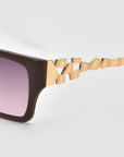 Close-up of For Art's Sake® Incomplete boxy square sunglasses featuring a brown acetate frame, purple-tinted lenses, and a unique gold geometric mosaic metal design on the temple arm against a plain light background.