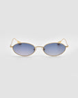 The Calla I glasses by For Art's Sake® feature modern oval gold metal frames with blue-tinted lenses, resting centered on a plain light gray background for a lightweight sculptural look.