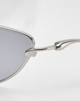 Close-up side view of For Art's Sake® Lake cat-eye sunglasses featuring a silver metal frame, gray lenses, sculpted temples, and hinge detail against a plain white background.