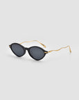Round black Totto sunglasses by For Art's Sake®, featuring dark lenses and gold sculpted temples in acetate and metal, displayed on a light gray background.