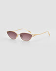The Tulip II cat-eye sunglasses by For Art's Sake® feature a bold acetate front, gold metal frames, and brown tinted lenses, shown on a light gray background.