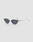 The For Art's Sake® Tulip II sunglasses feature silver cat-eye frames, dark tinted lenses, and sculptural accents, displayed on a light grey background.