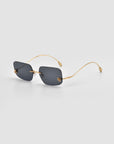 Magnolia sunglasses by For Art's Sake® feature rectangular dark lenses and slim gold arms, elegantly displayed on a light gray background.