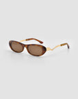 For Art’s Sake® Abstraction I: Brown oval sunglasses with dark lenses and bold, zigzag-patterned arms offer a comfortable statement look, shown on a plain light grey background.