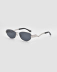 For Art's Sake® Abstraction II sunglasses showcase a sculptural frame in silver metal, oval dark lenses, and black temple tips, elegantly set against a plain light gray background.