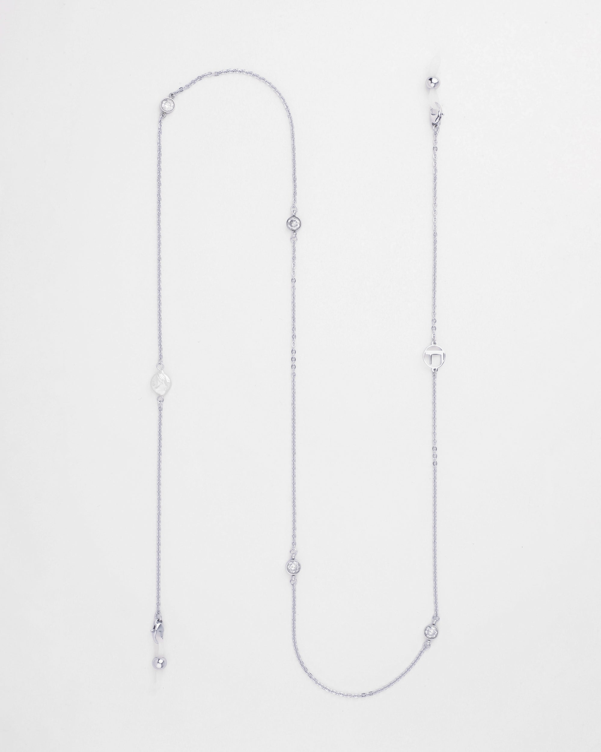 A delicate Wimbledon Glasses Chain with various small charm elements, including a heart, circular designs, and a freshwater pearl-like bead hanging from the ends. Palladium plated accents enhance its simple and elegant appearance, beautifully displayed on a white background. For Art's Sake®