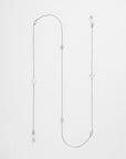 A delicate Wimbledon Glasses Chain with various small charm elements, including a heart, circular designs, and a freshwater pearl-like bead hanging from the ends. Palladium plated accents enhance its simple and elegant appearance, beautifully displayed on a white background. For Art's Sake®