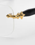 Close-up of the Claremont eyeglasses by For Art's Sake® from the Rose Garden collection, showcasing soft rectangular lenses. The transparent frame pairs with black temple arms embellished with gold stars near the hinge, set against a simple white background to emphasize their elegance.