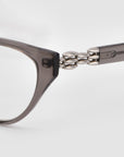 Close-up of For Art's Sake® The Act eyewear, showcasing its translucent gray frame and silver bead detailing on the temple hinge, set against a plain white background.