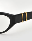Close-up of the Halo(X) sculptural acetate frames by For Art's Sake® in classic black, showcasing two gold 3D temple embellishments near the hinge against a plain, light background.