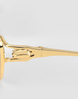 Close-up of the gold-colored sculptural hinge on For Art's Sake® Anita eyewear, featuring a decorative floral design against a plain light background.