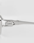 Close-up side view of the Anita eyewear by For Art's Sake®, featuring a sleek silver geometric metal frame with a distinctive hinge, set against a plain light gray background.
