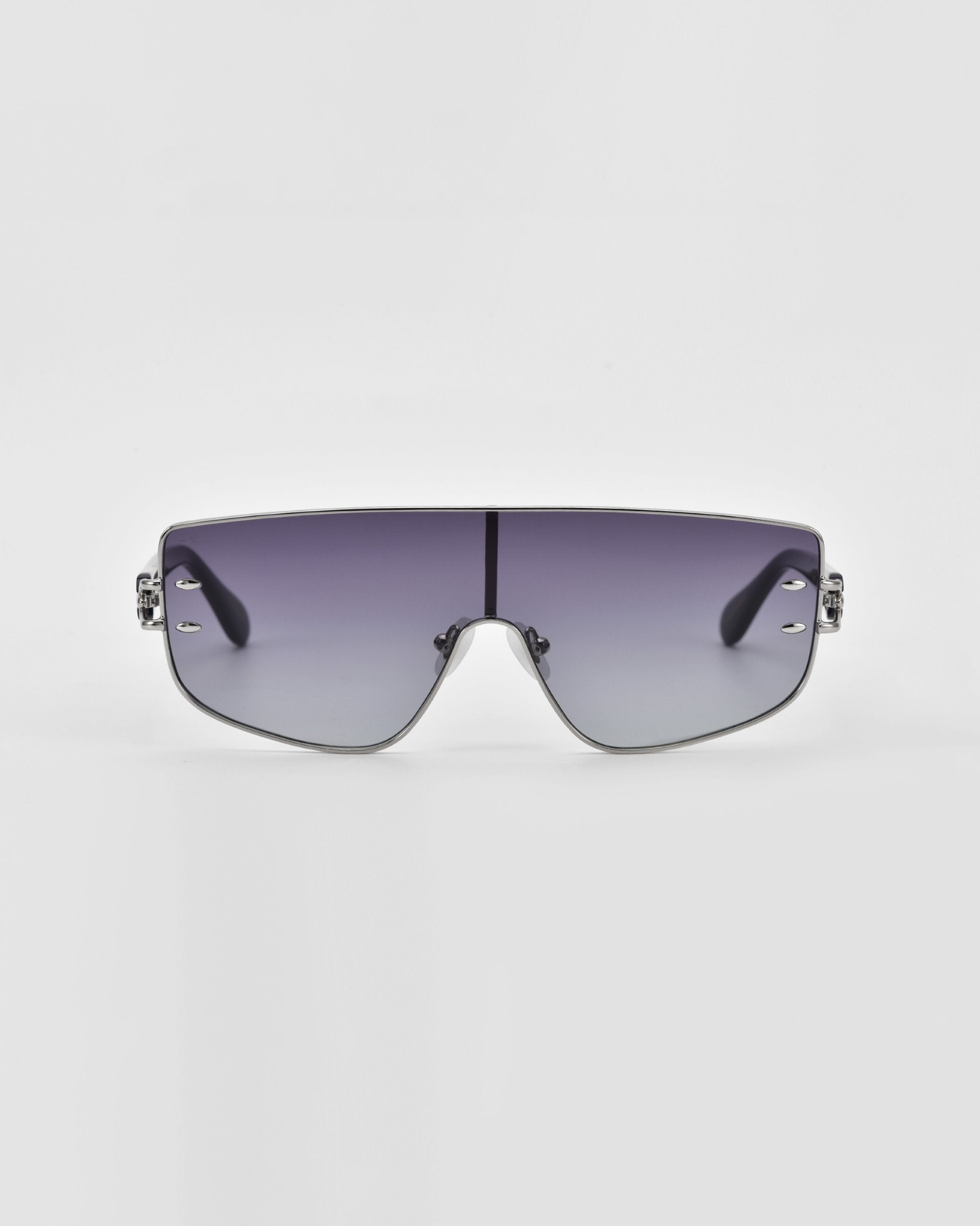 A pair of stylish, oversized For Art's Sake® Flare sunglasses with a silver frame and gradient lenses. The lenses transition from dark at the top to lighter at the bottom, and the frame has minimalistic, sleek detailing. This luxury eyewear piece stands out against a plain white background with its futuristic design.