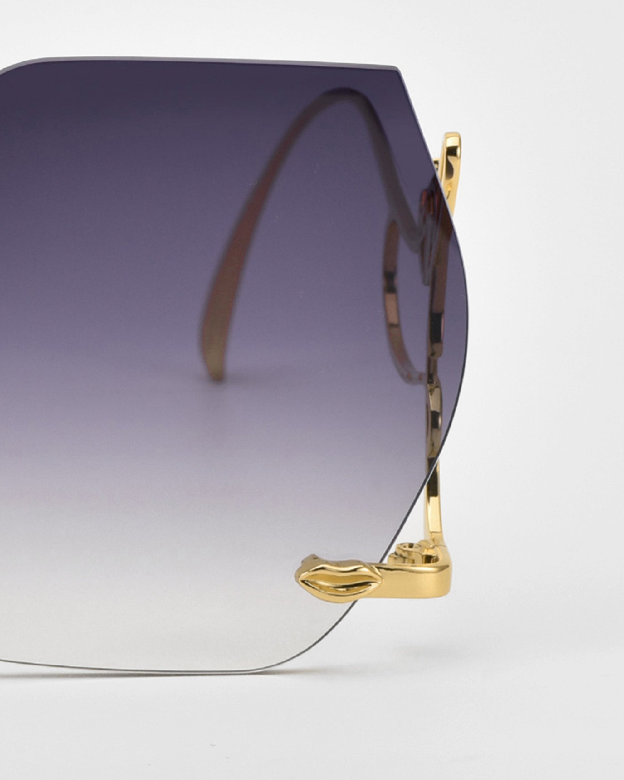 Close-up of For Art's Sake® Cry Me a River sunglasses, a limited edition with frameless gradient lenses and gold metal arms and hinges, displayed against a plain white background.