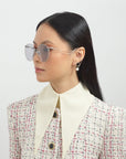 A woman with straight black hair looks left, wearing For Art's Sake® Birthday Cake-Blue round sunglasses and a textured white blazer with a cream pointed collar, set against a plain background.