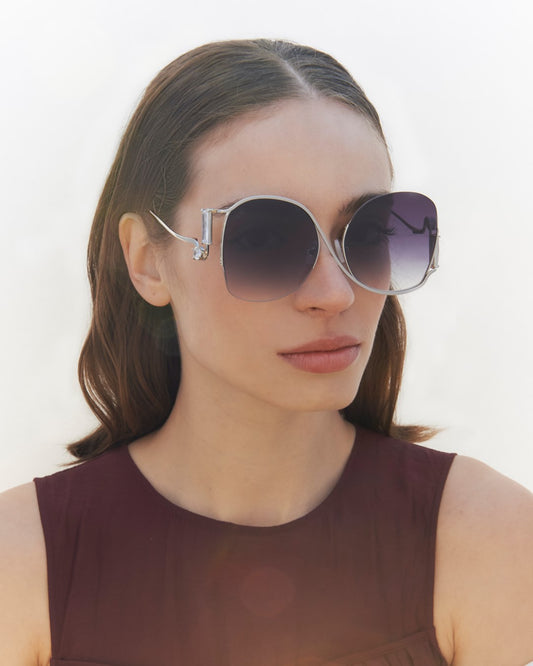 A model wearing the Sapphire sunglasses in Black.  Showing off the large gradient frames with silver lining. 