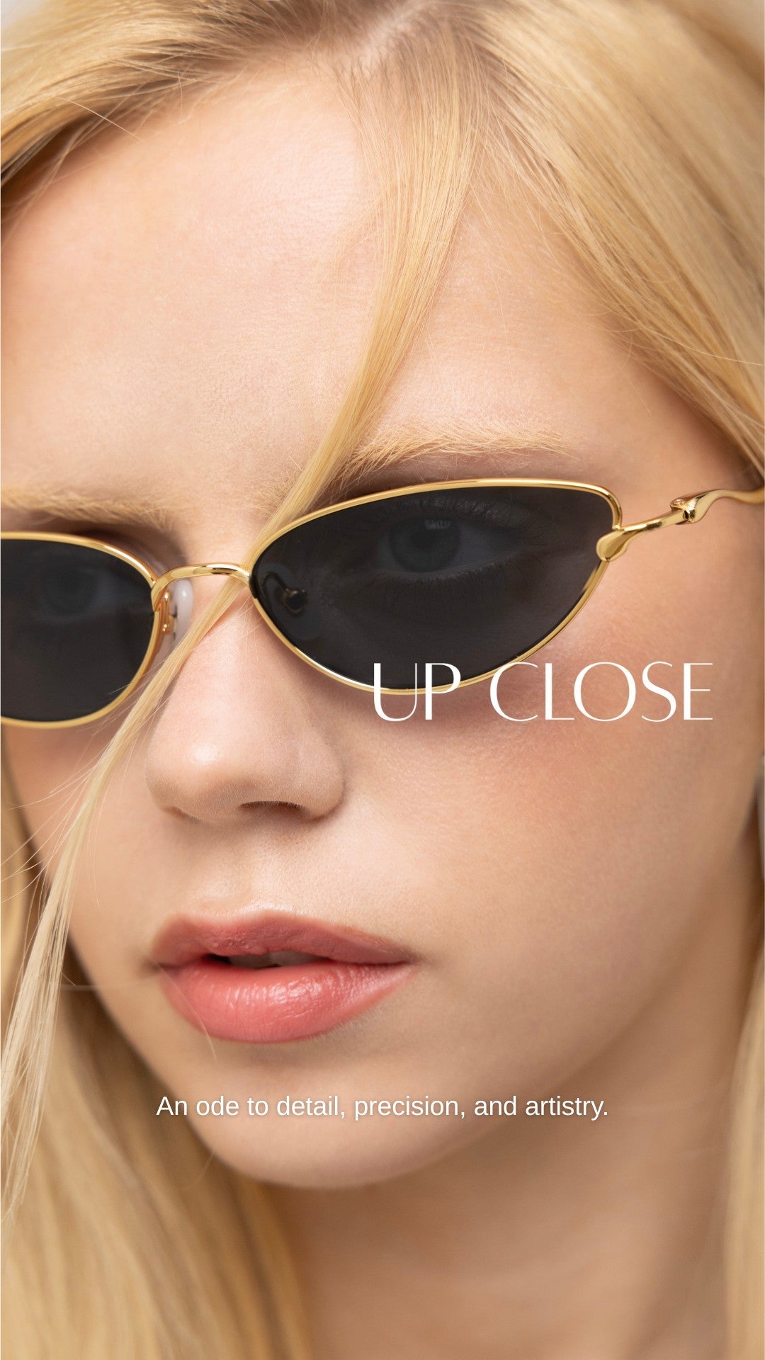 A close-up of a woman with blonde hair wearing black cat-eye sunglasses and light makeup. Text reads “UP CLOSE” and “An ode to detail, precision, and artistry.”.