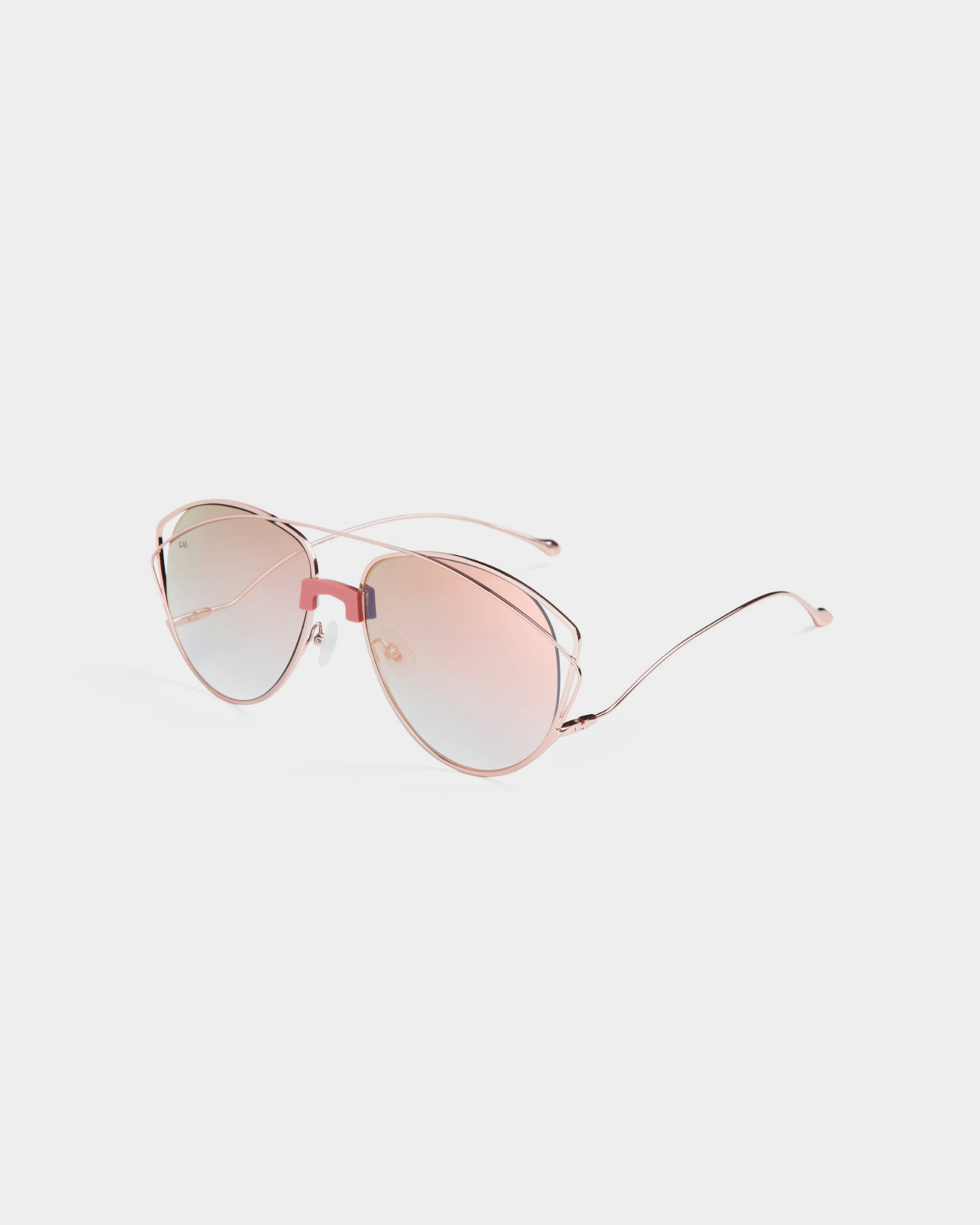 The Dark Eyes sunglasses by For Art's Sake® are stylish pink-tinted aviators with 100% UV protection and rose gold stainless steel frames, featuring thin metal arms and nose pads, displayed on a white background.