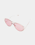 A pair of Dark Eyes sunglasses from For Art's Sake®, featuring thin, stainless steel frames and pink-tinted nylon lenses, resting on a white background. The frame design is minimalist with no visible embellishments, offering 100% UV protection and giving the sunglasses a sleek, modern look.