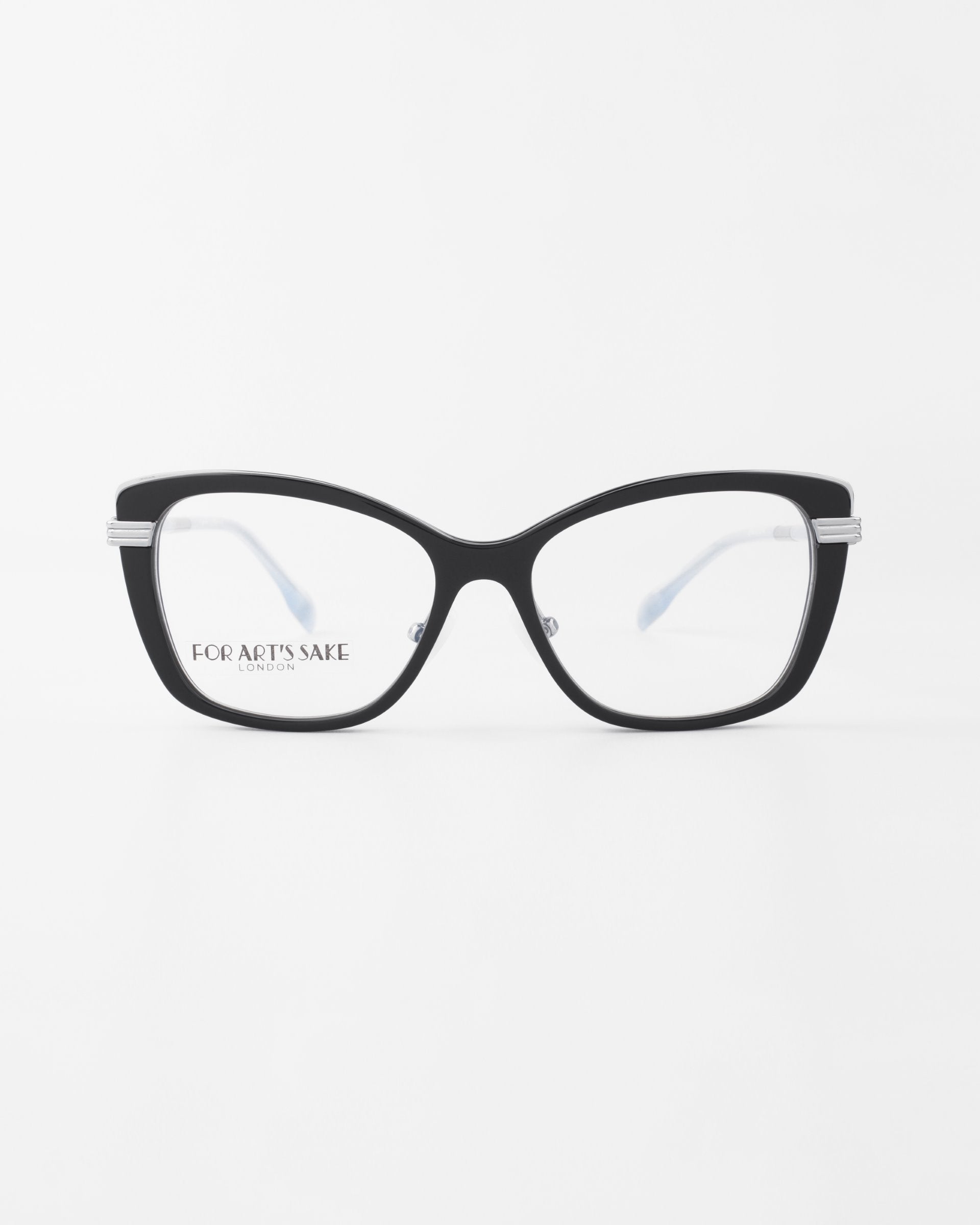 Amour by For Art's Sake®: Black cat-eye frames with clear lenses and adjustable nose pads, shown on a white background. "For Art’s Sake London" is printed inside the left lens.