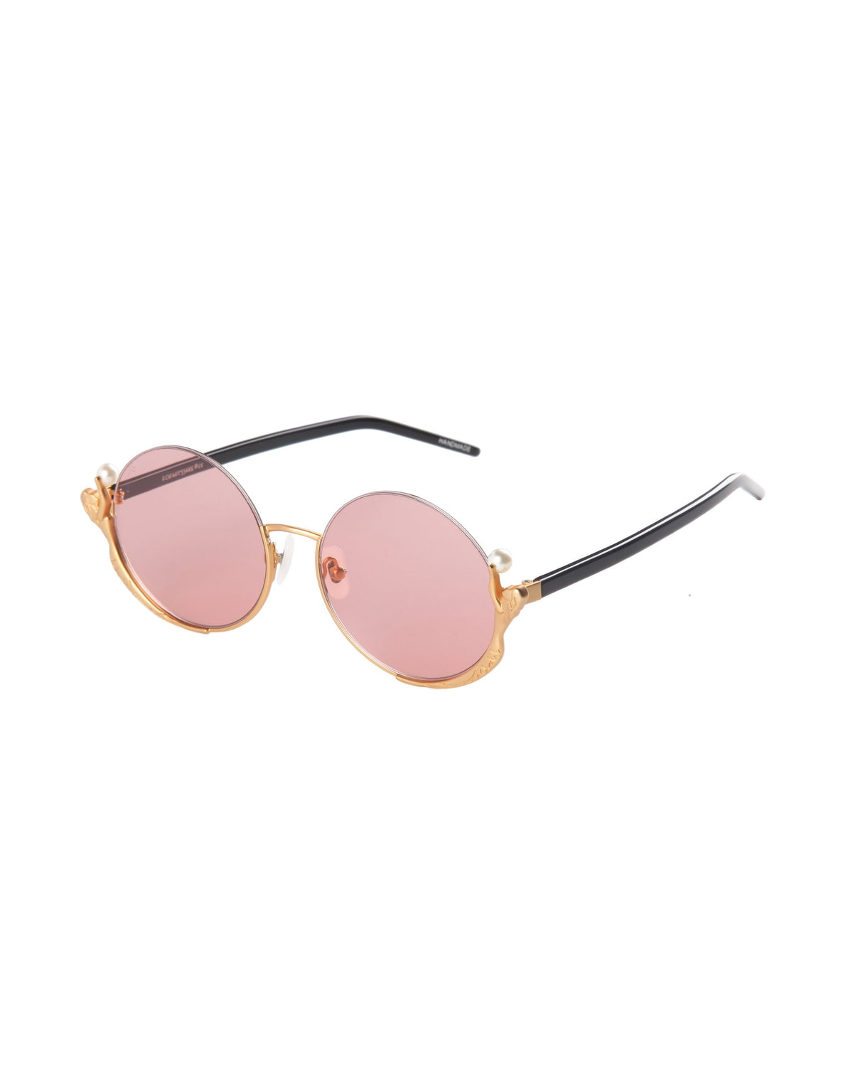 The Ariel sunglasses by For Art's Sake® feature round gold metal frames, black arms, and pink-tinted lenses—fashion-forward eyewear for a standout look, displayed on a white background.