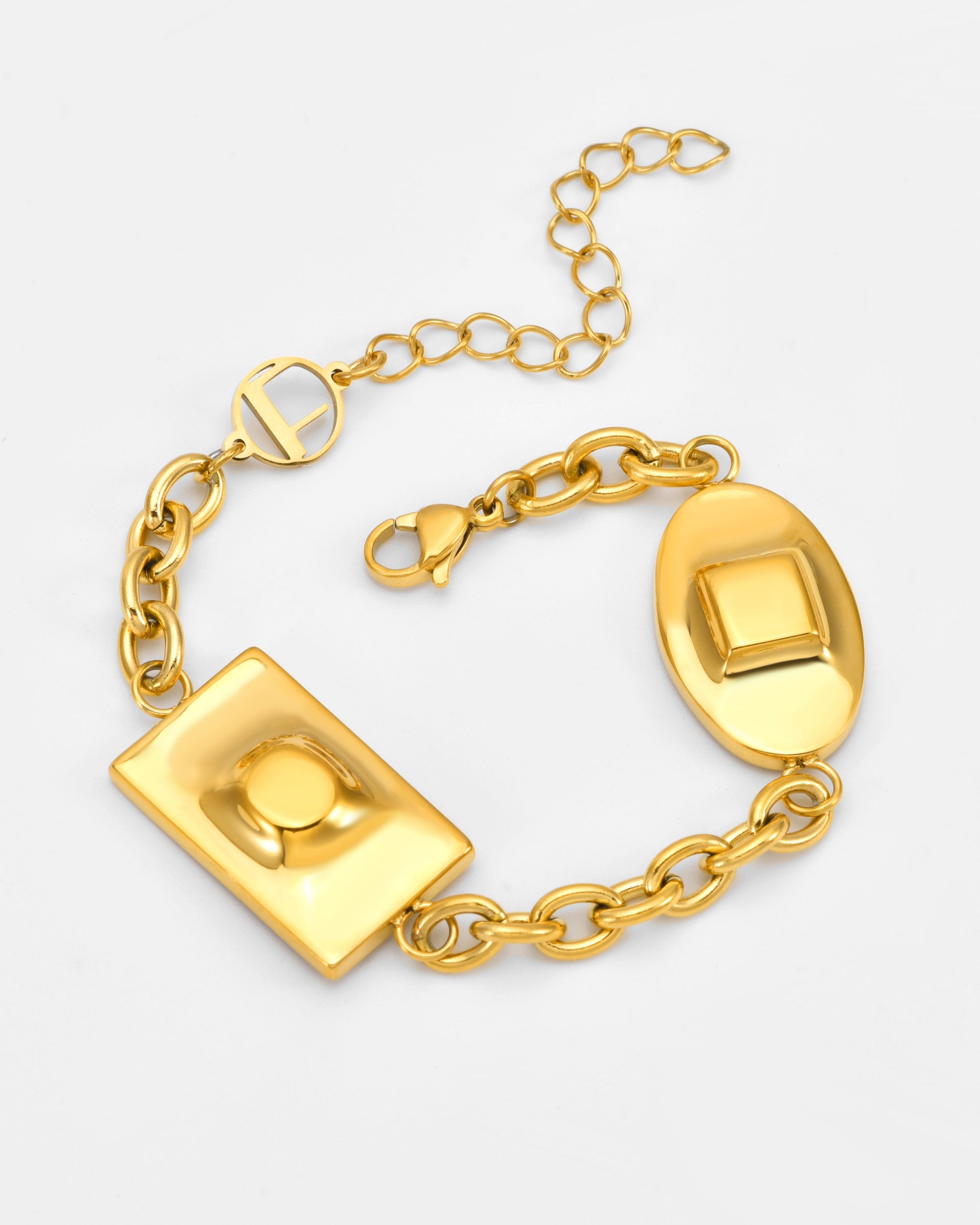 The Geometry Bracelet by For Art's Sake® is a gold chain with two raised, indented geometric charms—one rectangular, one oval—and an adjustable clasp. Shown on a plain light background.