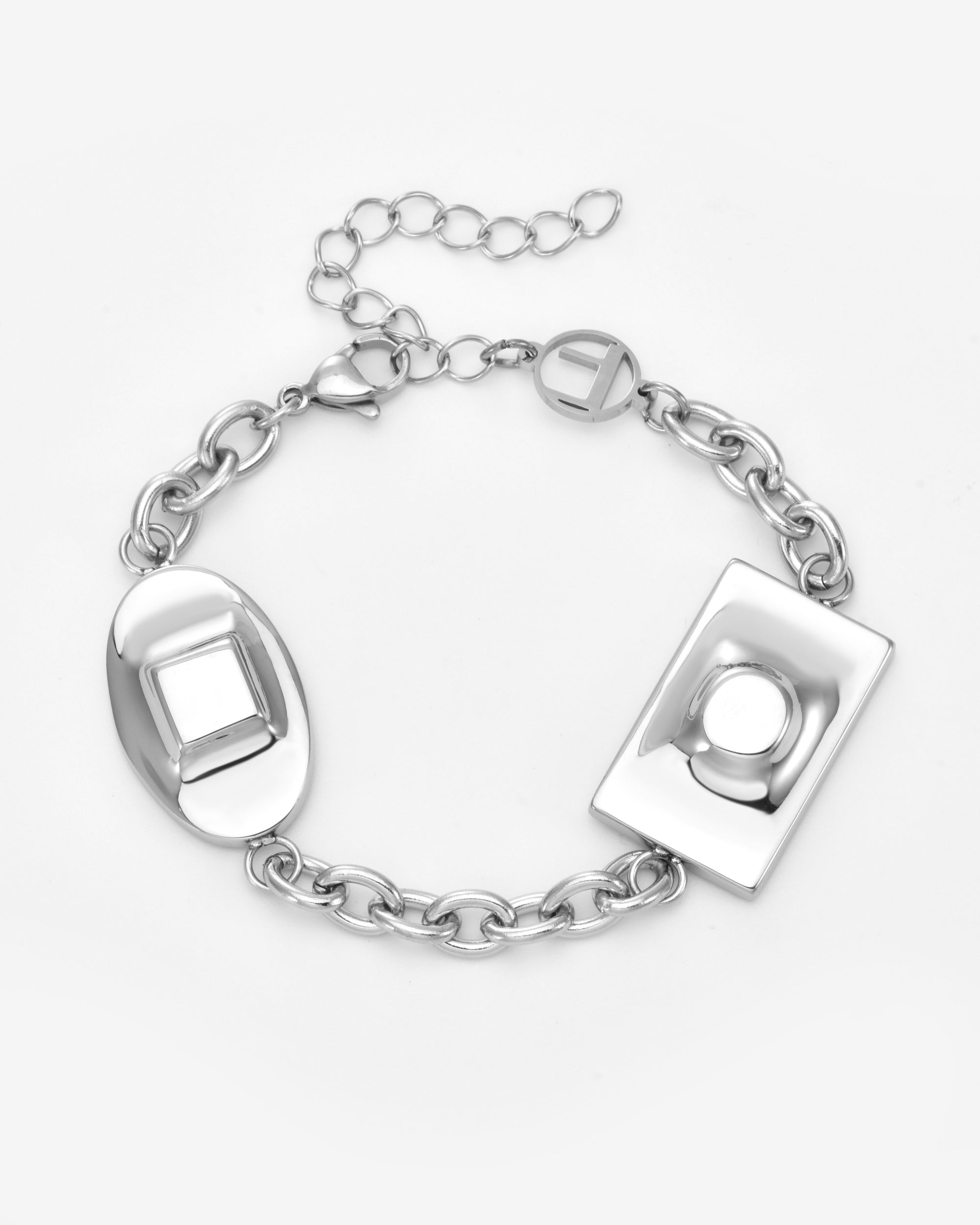 The Geometry Bracelet from For Art's Sake® is a silver chain with two large raised-design geometric charms—oval and rectangular—plus a lobster clasp, adjustable extender, and extra round charm for a modern touch.