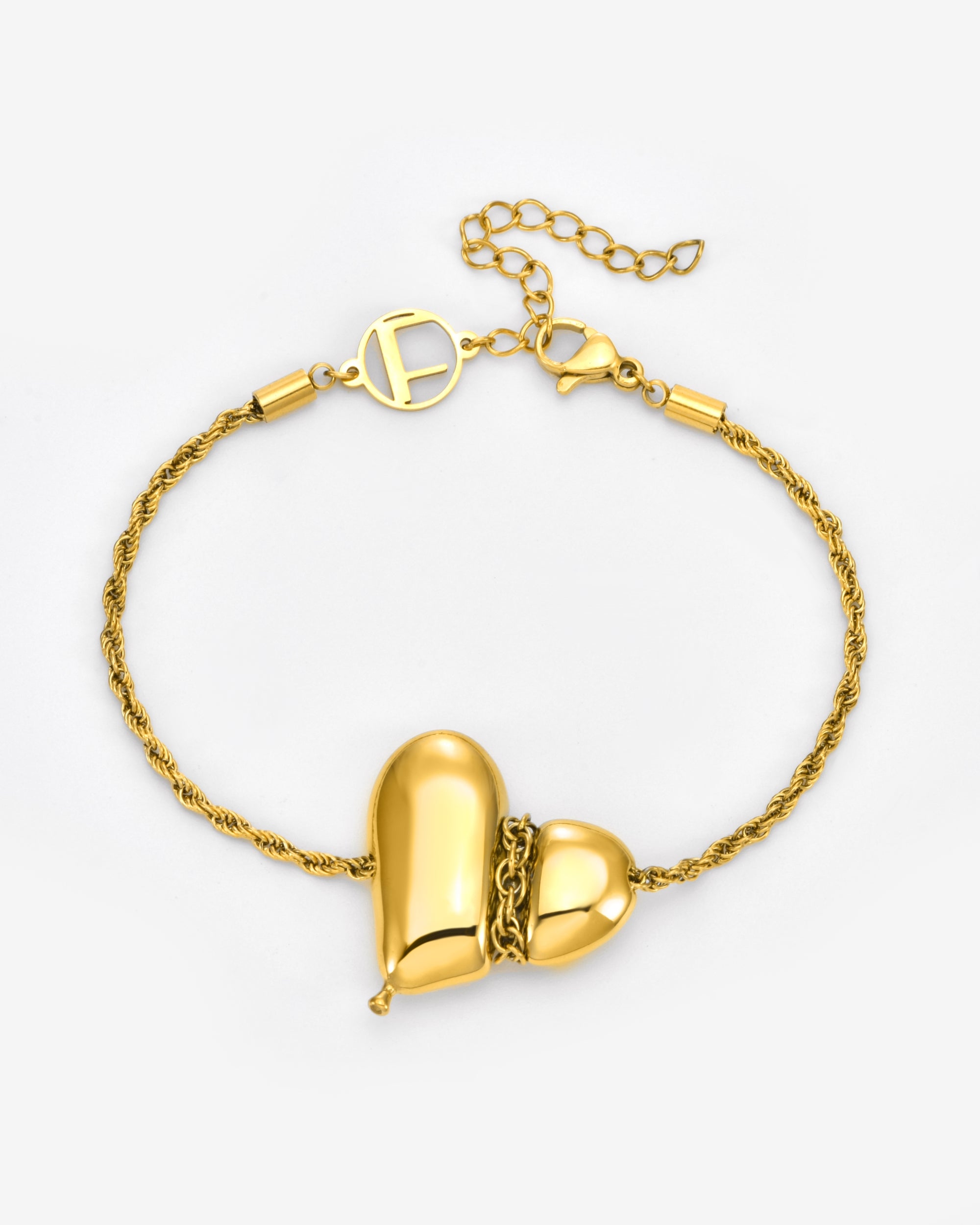 The Puffy Heart Bracelet by For Art's Sake® is a gold textured chain with a central heart-shaped pendant, split in two and joined by small gold links, finished with a decorative circular clasp.