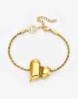 The Puffy Heart Bracelet by For Art's Sake® is a gold textured chain with a central heart-shaped pendant, split in two and joined by small gold links, finished with a decorative circular clasp.
