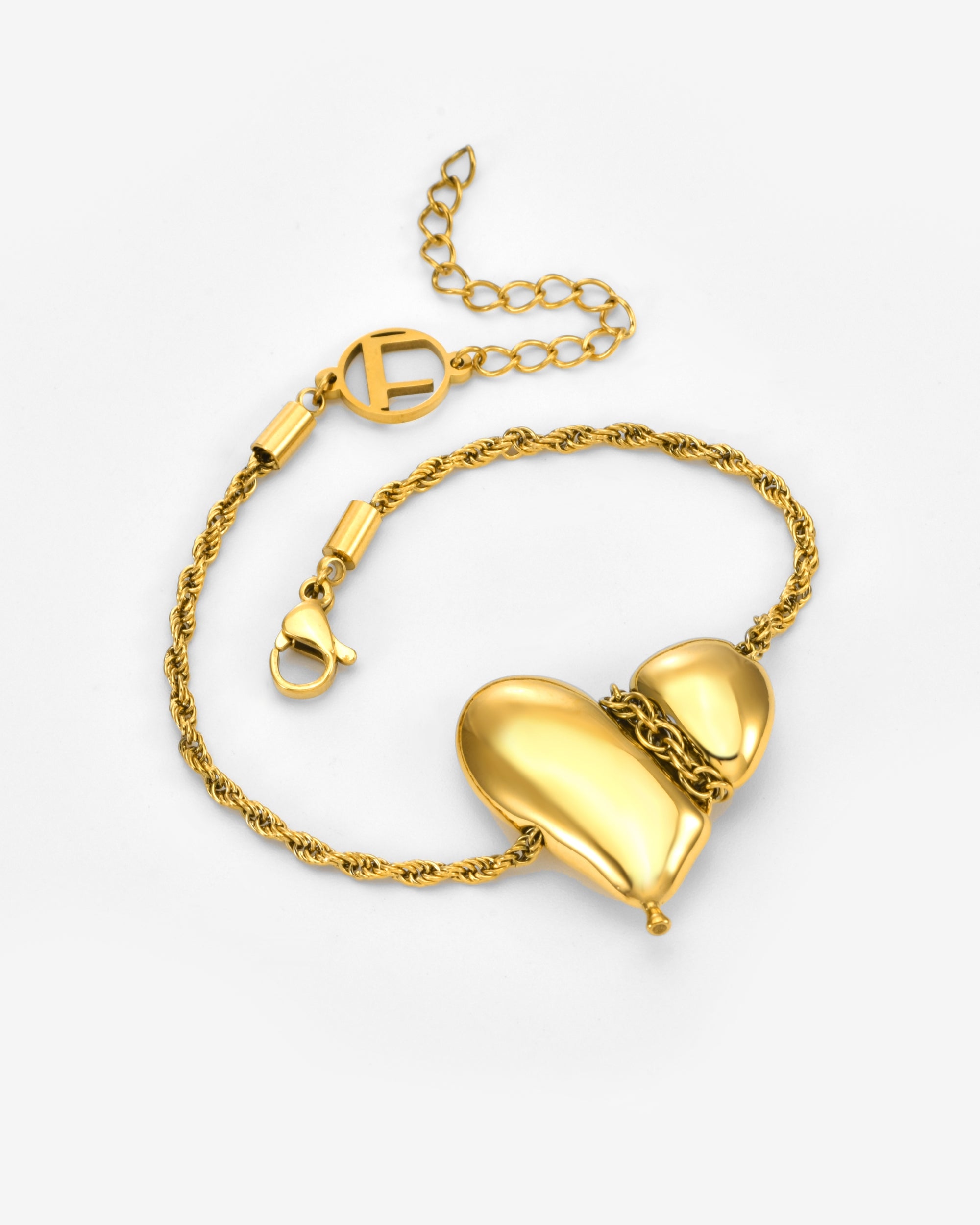 The Puffy Heart Bracelet by For Art's Sake® features a twisted gold chain with two shiny, smooth heart-shaped charms and a lobster clasp, displayed on a plain light background.