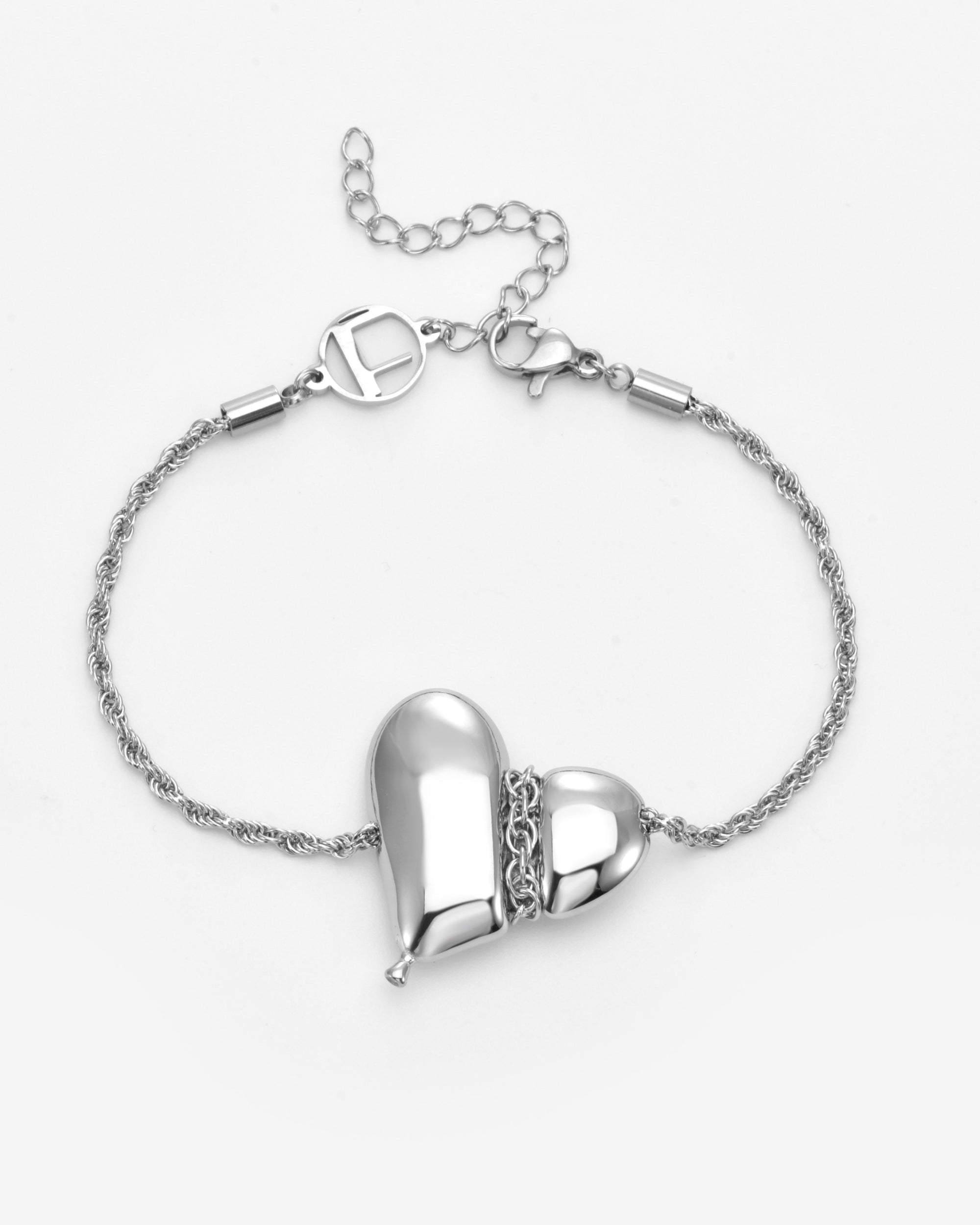 The Puffy Heart Bracelet by For Art's Sake® is a silver twisted chain with a shiny, asymmetrical puffed heart charm accented by a small chain detail and finished with an adjustable clasp.