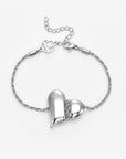 The Puffy Heart Bracelet by For Art's Sake® is a silver twisted chain with a shiny, asymmetrical puffed heart charm accented by a small chain detail and finished with an adjustable clasp.