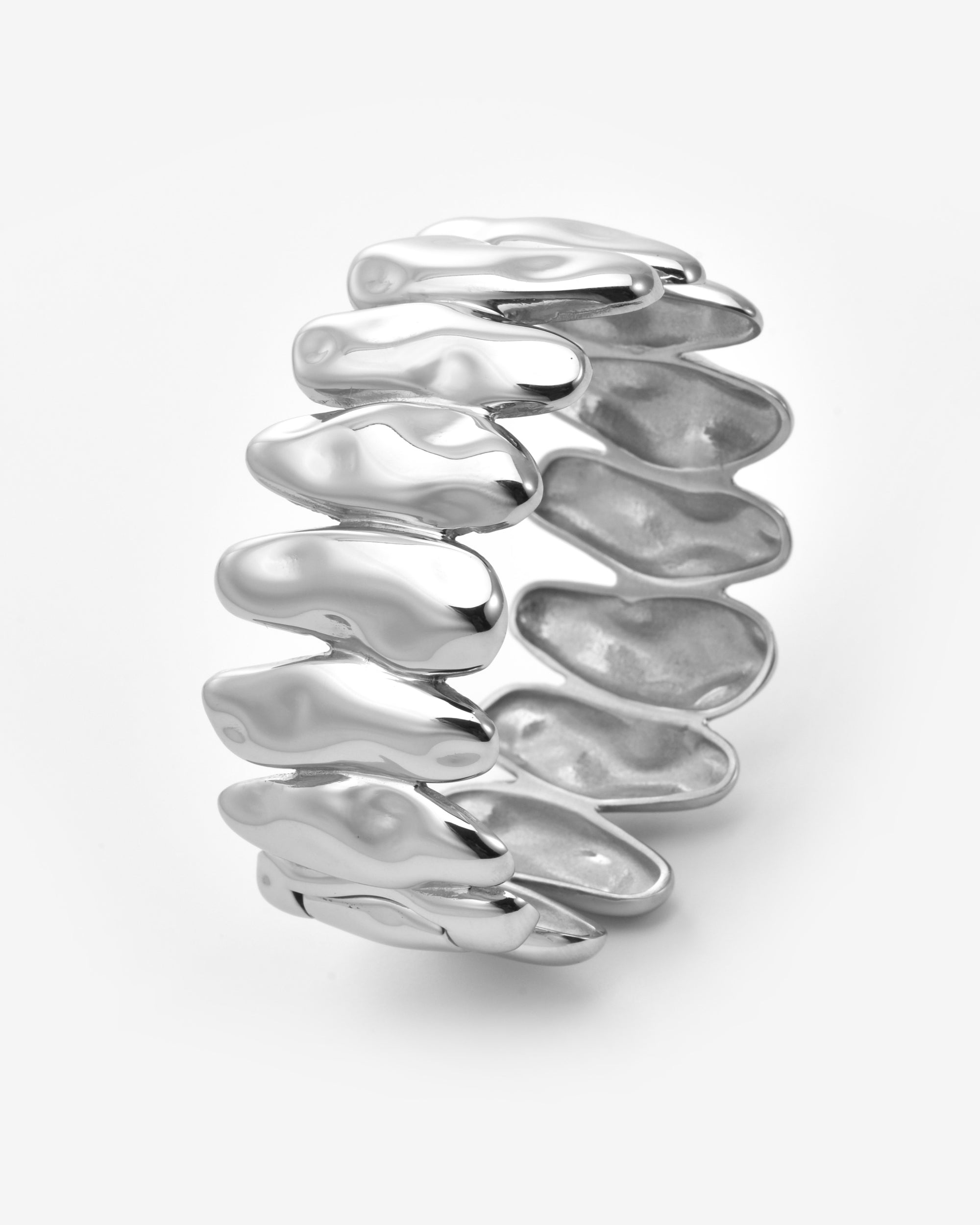 The Forms Bangle by For Art's Sake® features a wide silver organic shape with wavy, overlapping segments for a fluid, modern stacked look. The shiny metal bracelet stands upright against a plain white background.