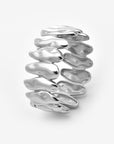 The Forms Bangle by For Art's Sake® features a wide silver organic shape with wavy, overlapping segments for a fluid, modern stacked look. The shiny metal bracelet stands upright against a plain white background.