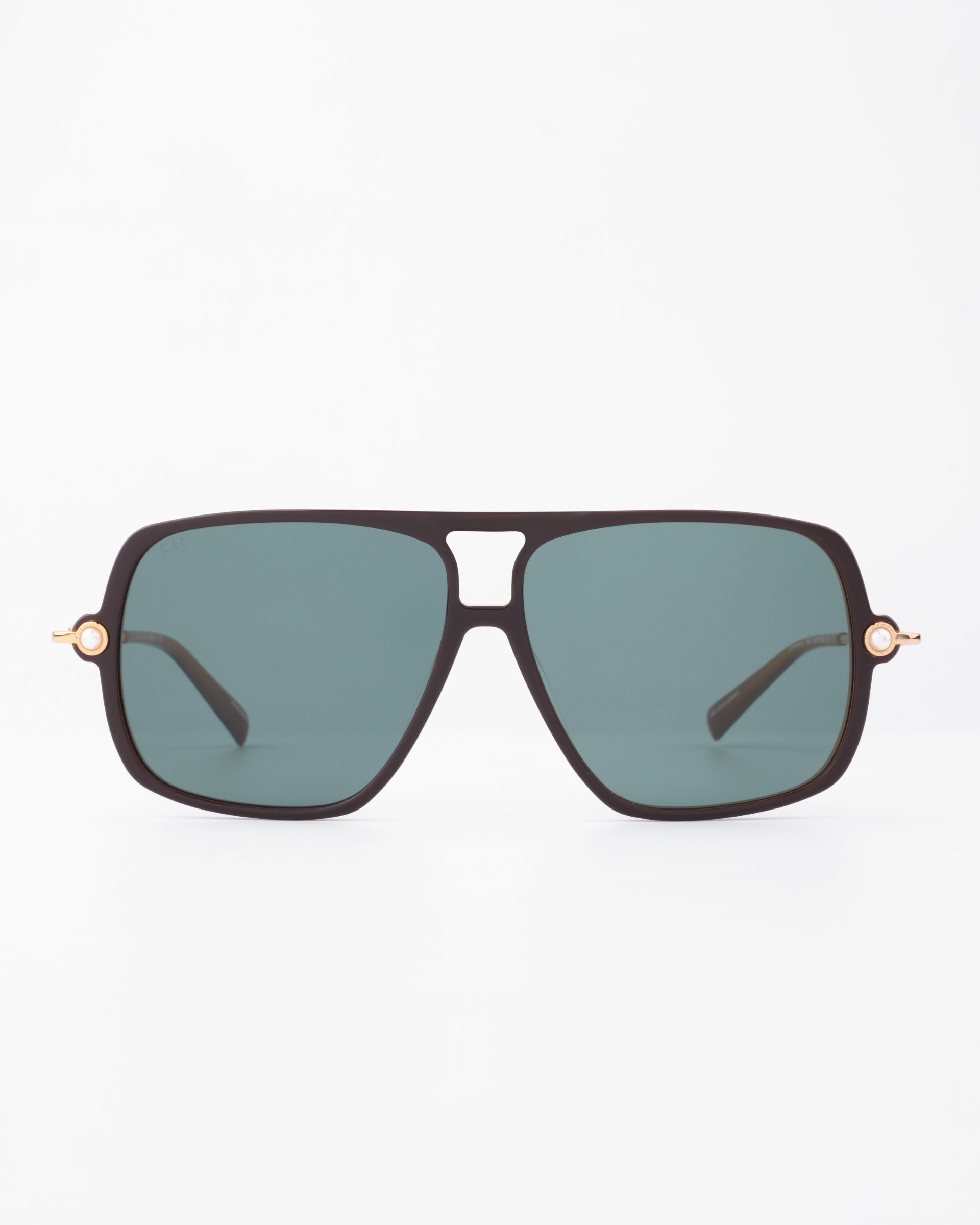 A pair of stylish black sunglasses with a rectangular frame and dark green lenses. The For Art's Sake® Cinnamon Green sunglasses feature unique 18-karat gold-plated accents near the hinges, adding a touch of luxury to the design. The background is plain white.