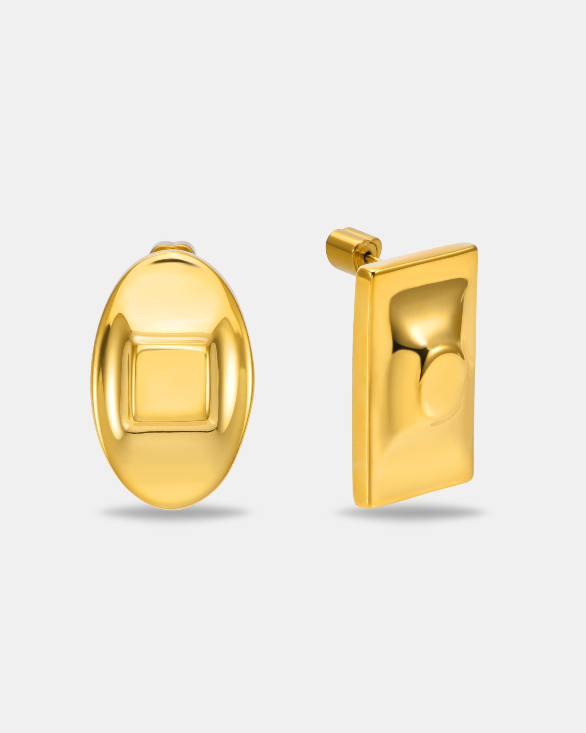 The Geometry Earrings by For Art's Sake®: a modern gold pair featuring an oval stud with a raised square center and a rectangular stud with a raised circular center, displayed on a plain background.