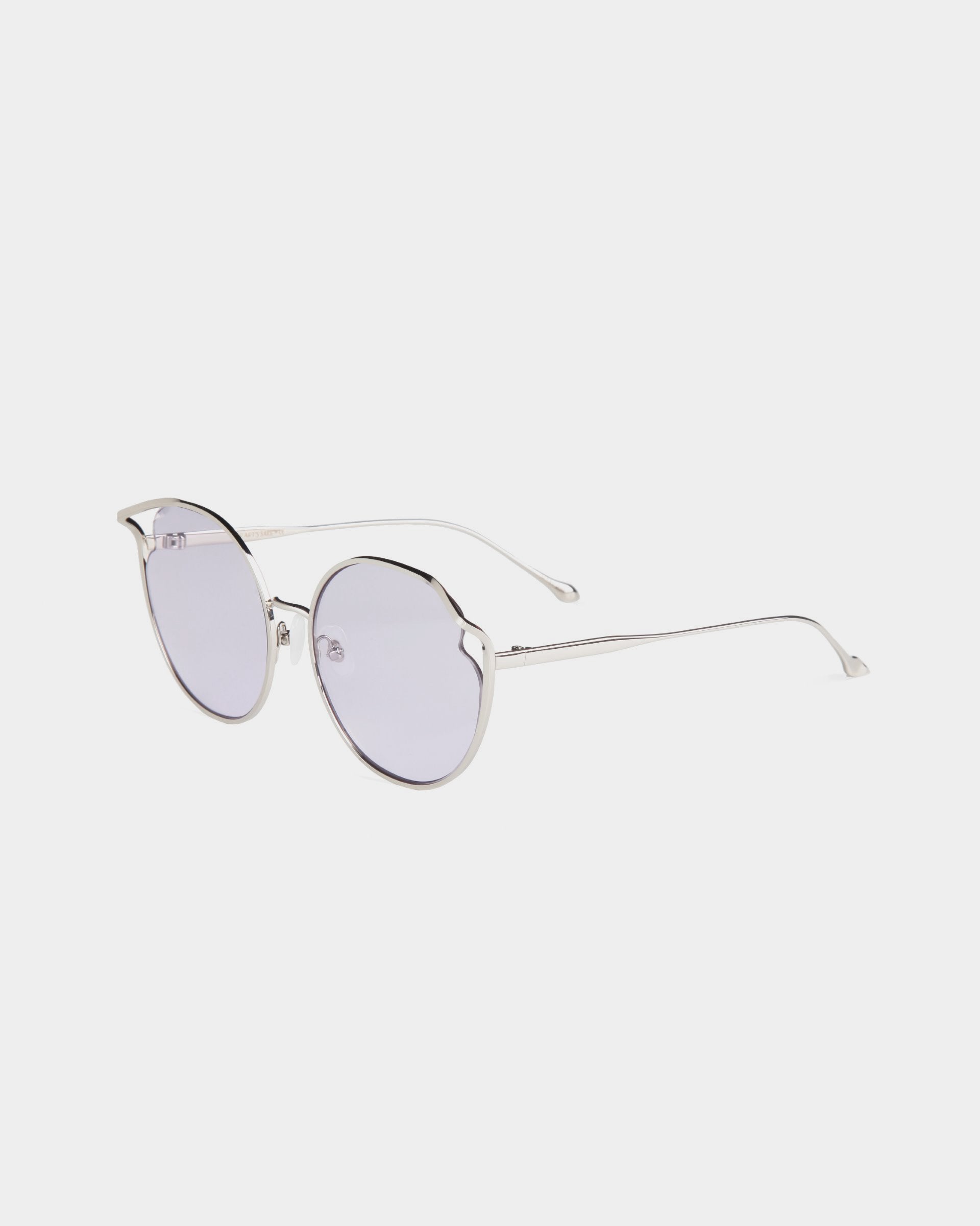 Round sunglasses with thin, silver metal frames and lightly tinted, nylon lenses are displayed against a plain white background. The design features slightly raised corners above the lenses for a subtle cat-eye effect. Each pair of Cat by For Art's Sake® provides UVA & UVB protection for your eyes.