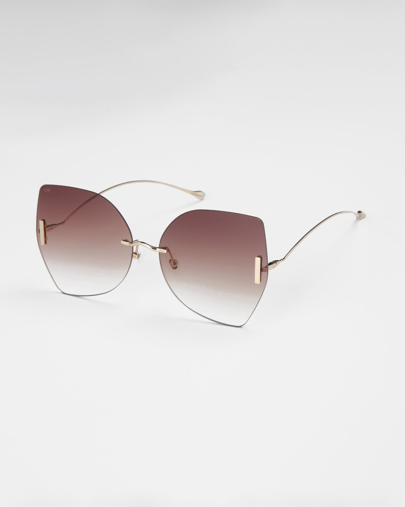 Introducing the Starlight sunglasses by For Art's Sake®—a pair of stylish shades featuring large, gradient lenses that transition from dark at the top to lighter at the bottom. These rimless lenses are connected by thin, gold-colored wireframes and include Jadestone nose pads, offering both a sleek look and enhanced comfort against a plain white background.