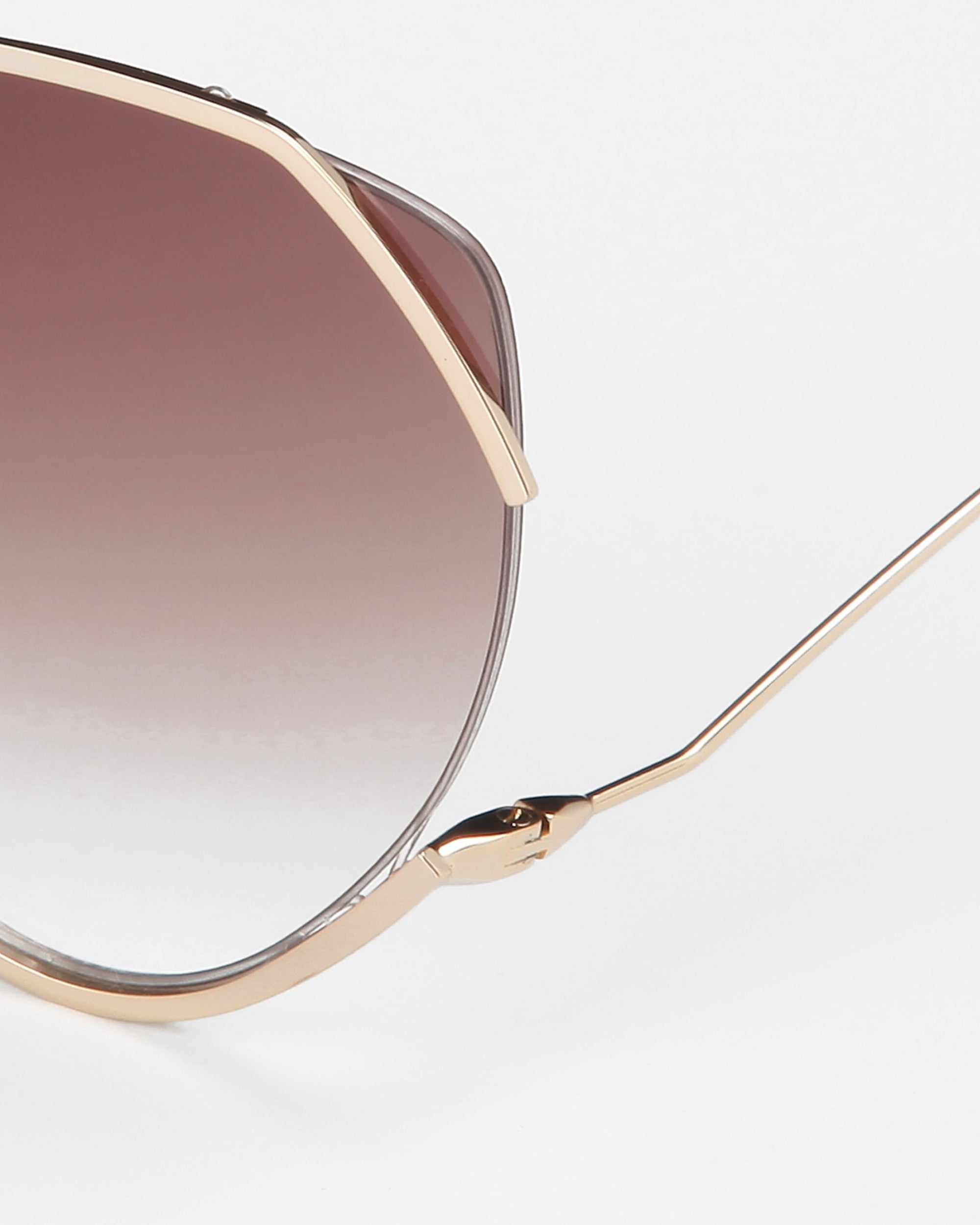 Close-up of For Art&#39;s Sake® Wonderland sunglasses featuring a gold geometric frame, gradient brown lenses, jadestone nose pads, and 100% UV protection against a plain white background.