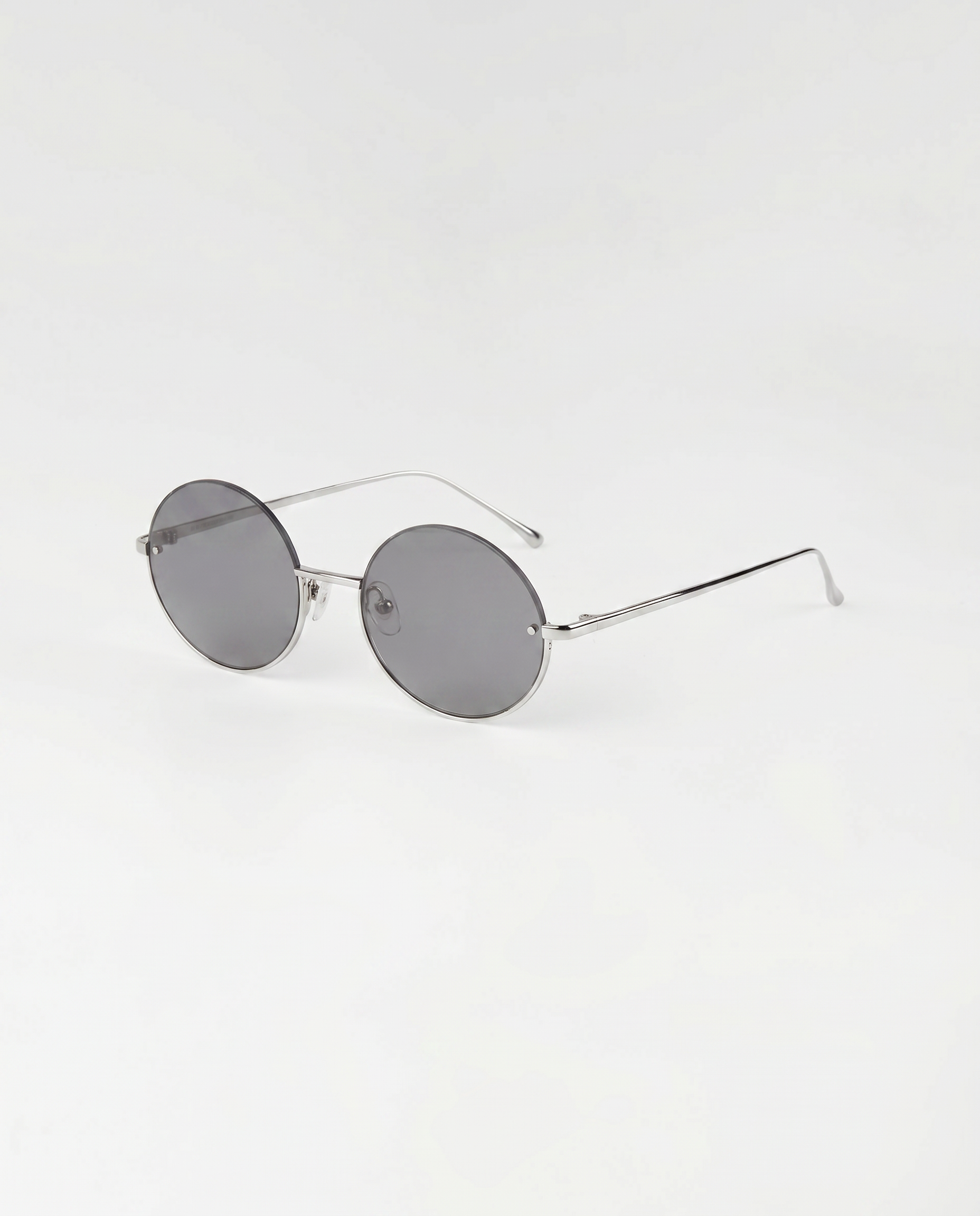 The For Art's Sake® Skyline-Grey sunglasses feature thin silver metal frames and dark tinted lenses, shown next to minimalist earrings on a plain white background.