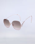 Lemonade (Last Piece) statement sunglasses by For Art’s Sake® feature rose gold, thin and delicate frames adorned with decorative faux pearls at the temple tips. The oversized lenses are gradient-tinted, adding a touch of elegance, all set against a plain light gray background.