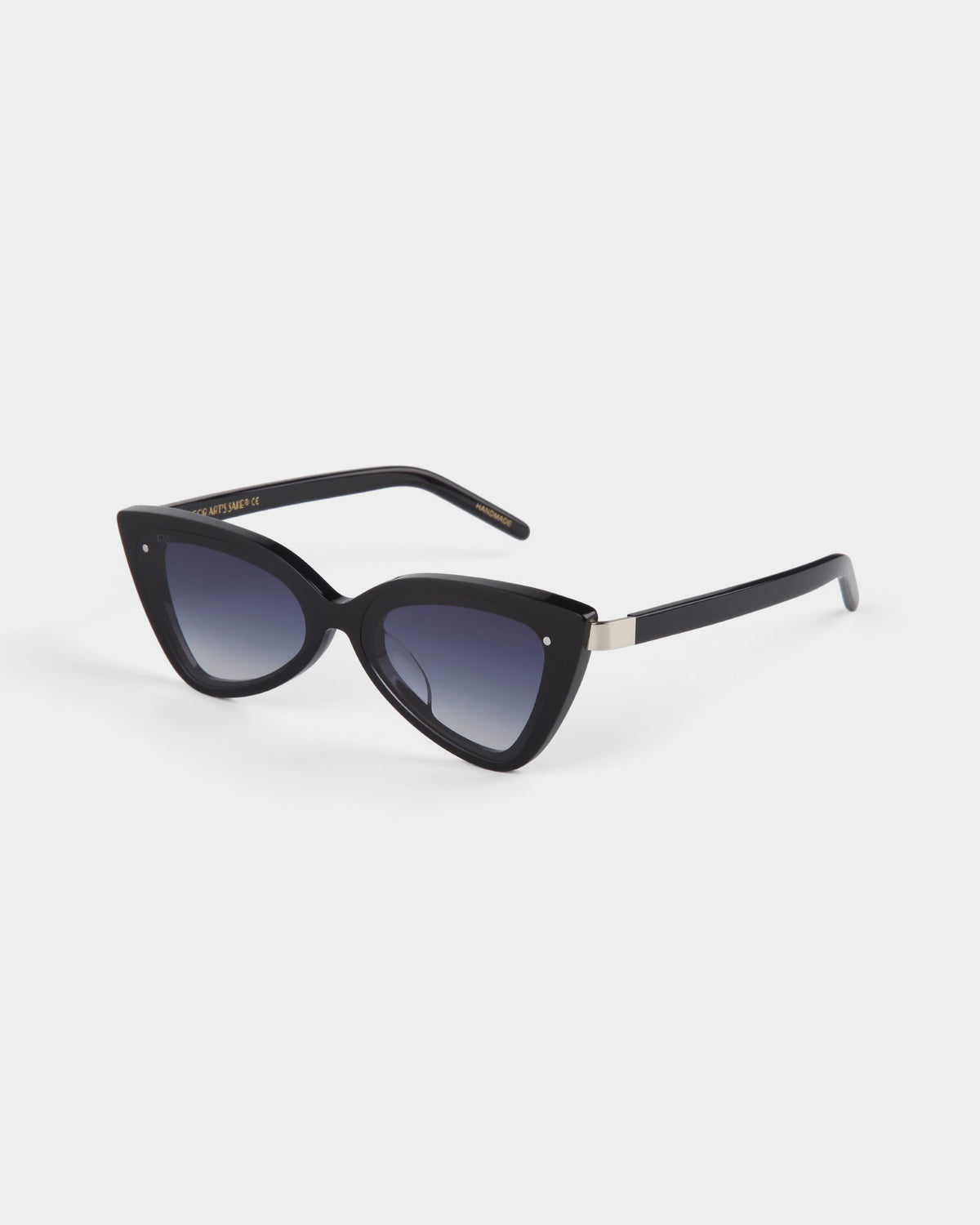 Introducing the Mad Mad sunglasses by For Art's Sake® – a pair of sleek, black cat-eye sunglasses with dark tinted lenses and a glossy acetate finish. These UVA & UVB-protected sunglasses feature small metallic details on the upper corners of the frames and a subtle logo on the arms. The design is modern and stylish, perfect for a chic look.