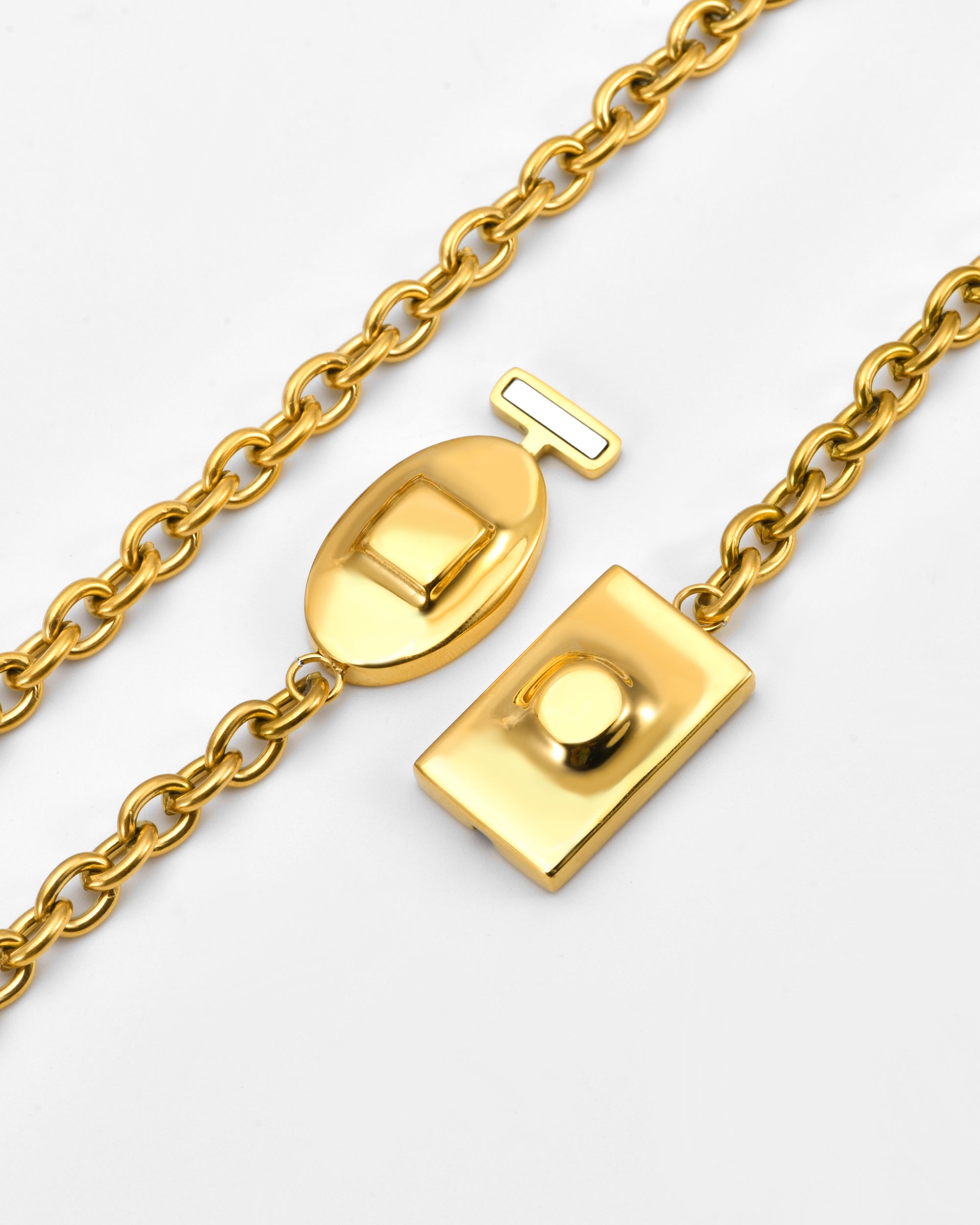 A close-up of The Geometry Necklace by For Art's Sake®, featuring a gold chain and distinctive rectangular and oval clasp, displayed open against a white background.