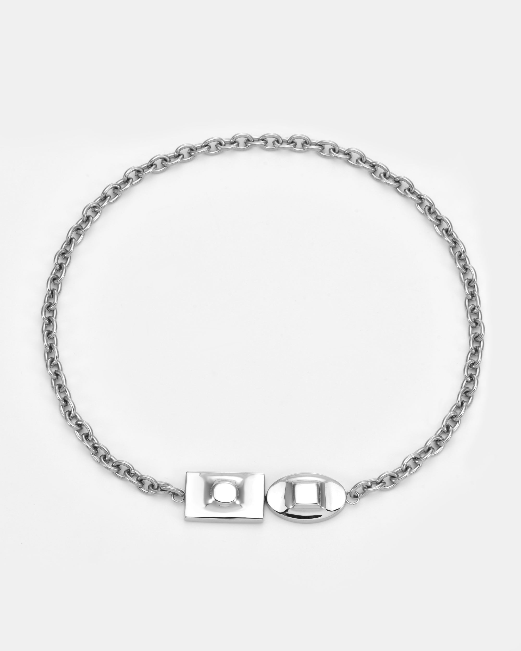 The Geometry Necklace by For Art's Sake® is a silver chain with round links, geometric charms, and a modern rectangular and oval front clasp, shown on a plain light gray background.