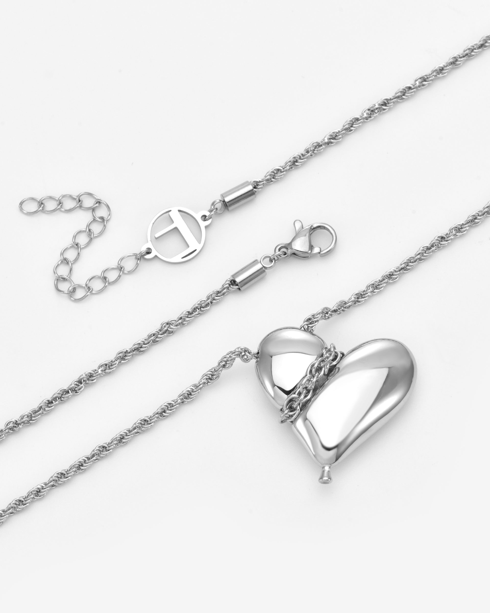 For Art's Sake® The Puffy Heart Pendant is a silver rope chain necklace with a shiny puffed heart charm partially wrapped by the chain, plus an adjustable extension and lobster clasp.