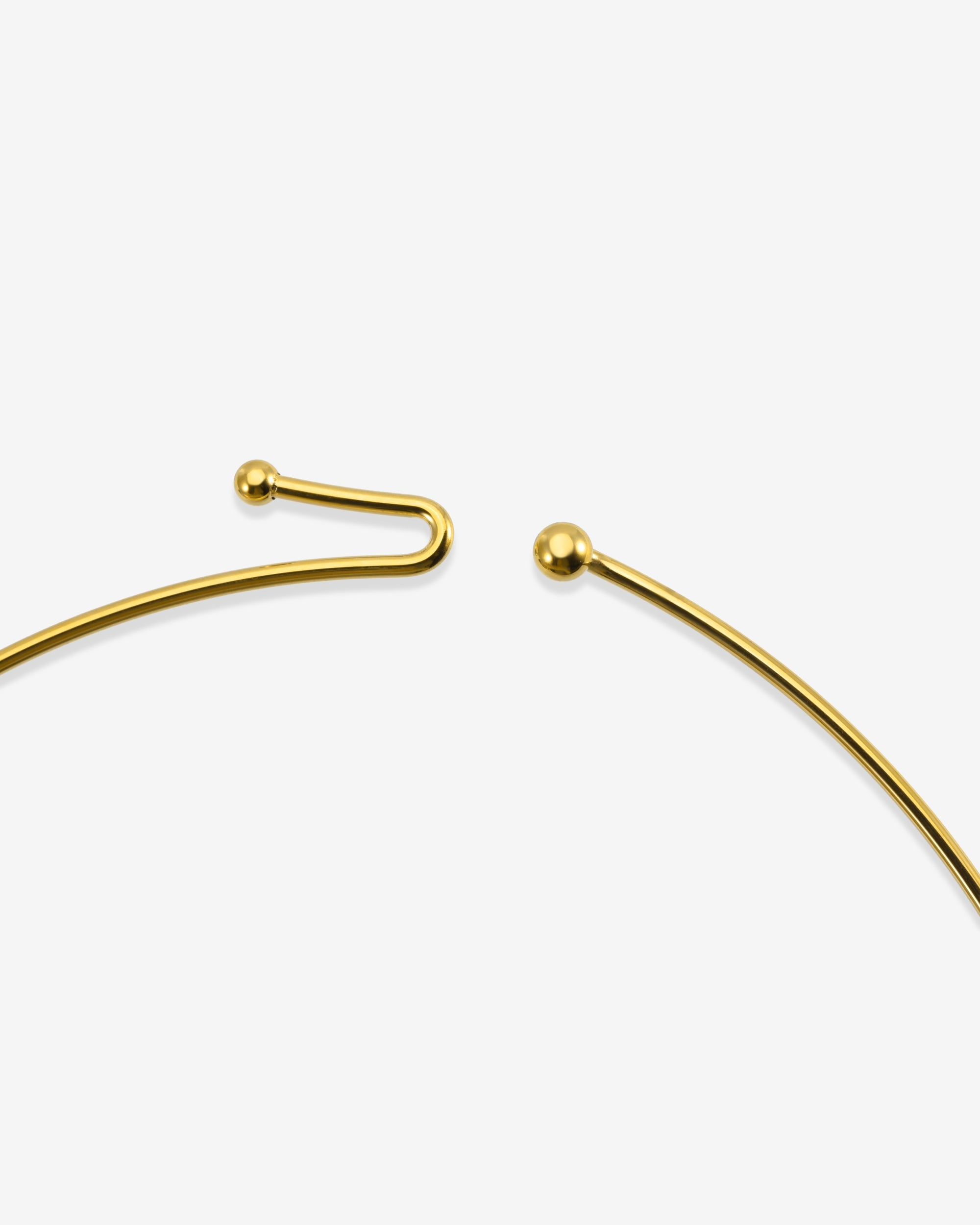 Close-up of The Rose Choker by For Art's Sake® on a white background, highlighting its delicate gold design with a small ball at one end and a curved hook at the other.