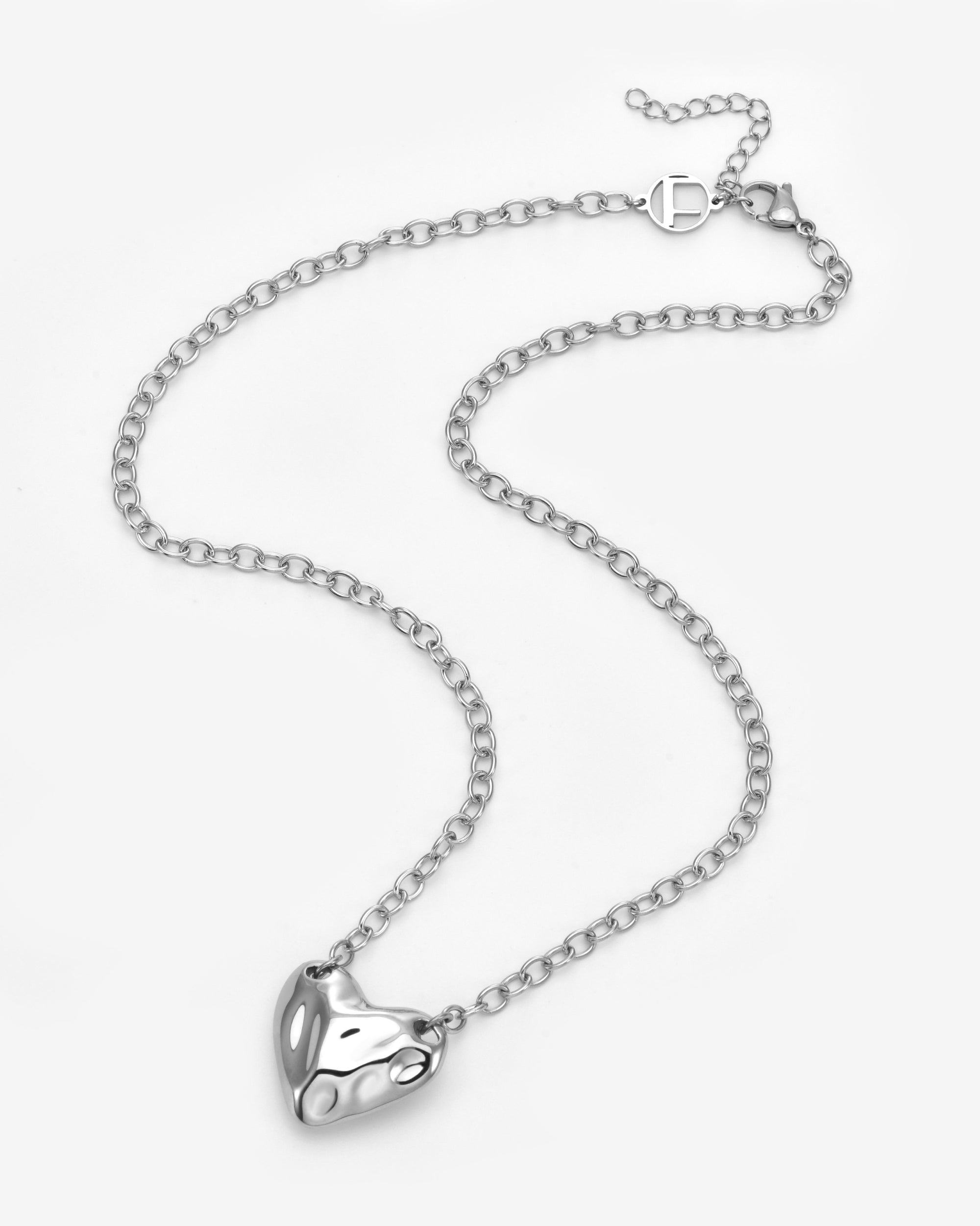 The Sculpted Heart Necklace by For Art's Sake® features a shiny, sculptural heart pendant on a delicate silver chain, displayed against a white background.
