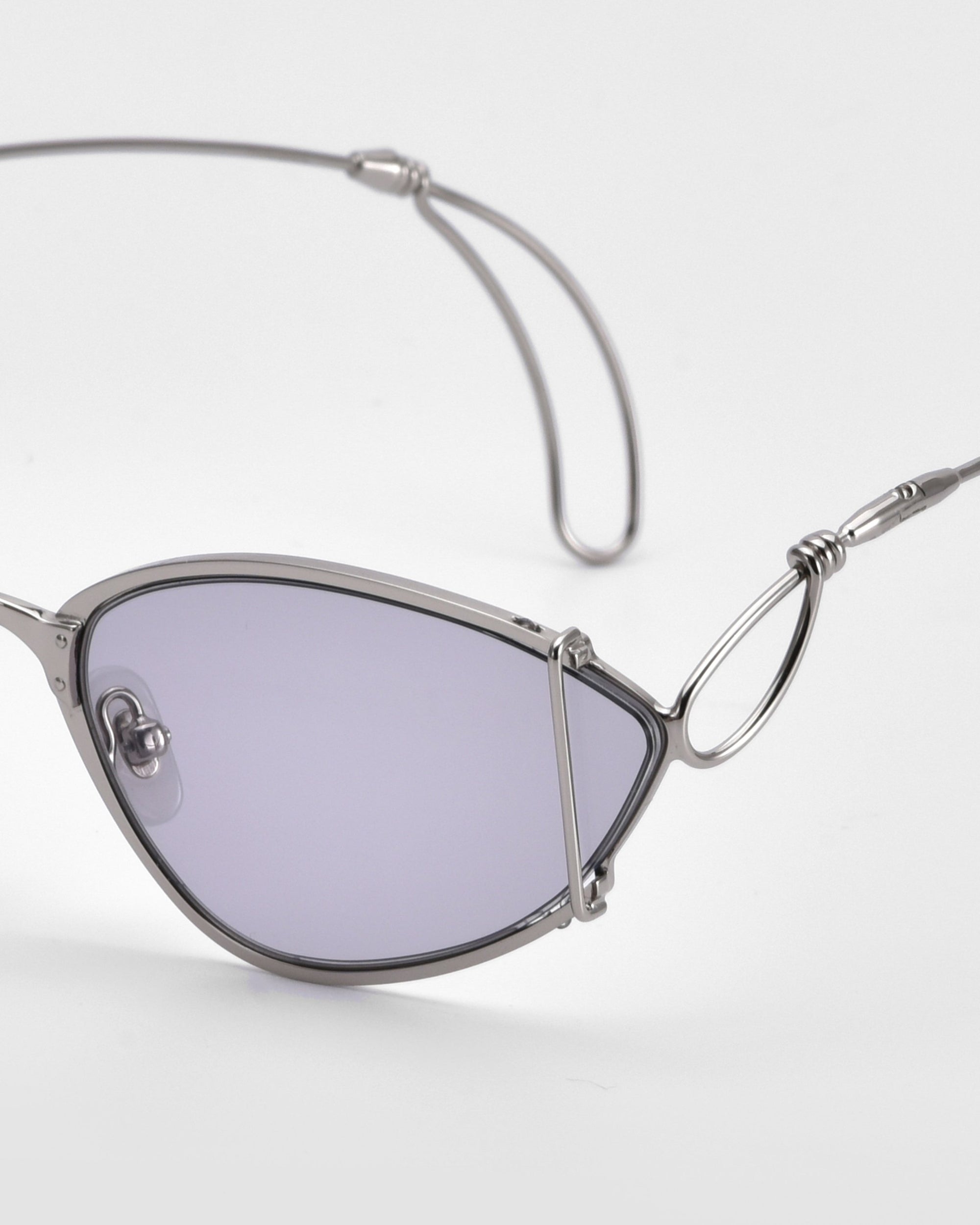 A close-up of For Art&#39;s Sake® Ornate sunglasses featuring a modern almond shape, edgy metal frame, and light purple-tinted lenses, set against a plain white background.